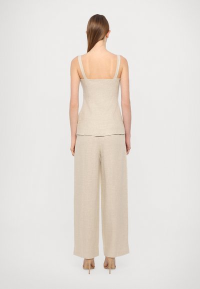 Beige linne tanktopp med firkantet ryggdesign, paret med vide bukser som har en teksturert finish og minimalt med hardware.