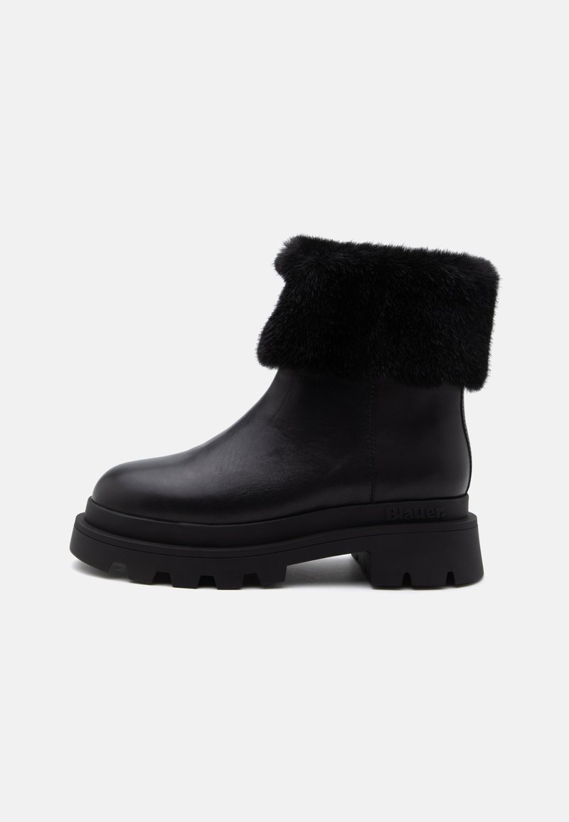 Bottine en cuir noir avec semelle à gros crampons épaisse et revers en fourrure noire replié autour du haut, vue de profil sur fond blanc.