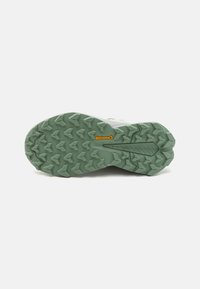 Zelena gumijasta podplat z teksturiranim vzorcem angularnih izboklin za oprijem. V bližini pete ima rumen logo Continental.