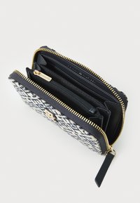 Zippered wallet in navy and white patterned fabric with gold hardware. Interior features multiple card slots and a zippered coin pocket.