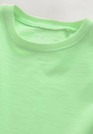 T-shirt en coton vert clair avec un col rond et des manches courtes. Texture lisse avec un léger éclat. Le nom de la marque "NEXT" est visible à l'intérieur du col.