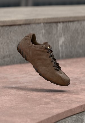 Brązowy sportowy but zamszowy z gumową podeszwą, teksturowaną cholewką i brązowymi sznurowadłami. Posiada trzy subtelne paski po bokach.