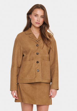 Brown suede jacket with a notched collar, front buttons, and two large pockets. The fabric has a smooth texture and a tailored fit.