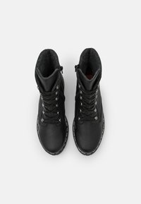 Bottines en cuir noir avec une doublure en polaire grise texturée, œillets en métal et couture blanche contrastante autour de la semelle.