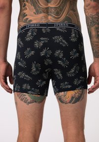 Black patterned boxer briefs with a JP1880 logo waistband, featuring a tropical leaf design in white and blue tones, soft cotton material.
