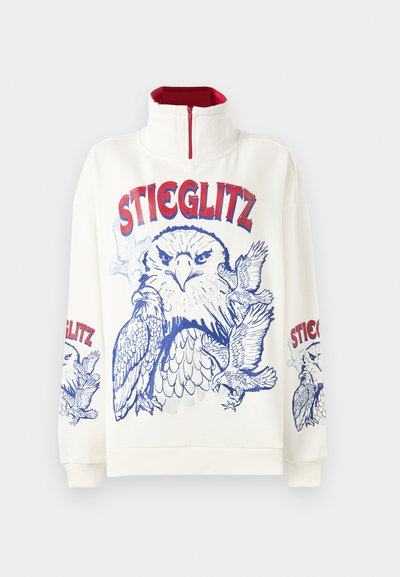 Felpa bianca con collo alto e zip rossa. Presenta una stampa grafica blu di un'aquila e il testo "STIEGLITZ" in rosso e blu.