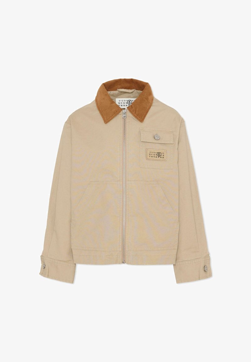 Giacca beige con colletto in velluto a coste marrone, chiusura frontale con cerniera, una tasca con bottone e due tasche applicate laterali. Materiale in cotone resistente.