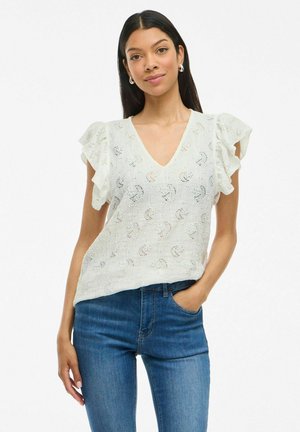 Blusa bianca a maniche corte con maniche arricciate e scollo a V, caratterizzata da un motivo testurizzato e tessuto leggero, abbinata a jeans blu.