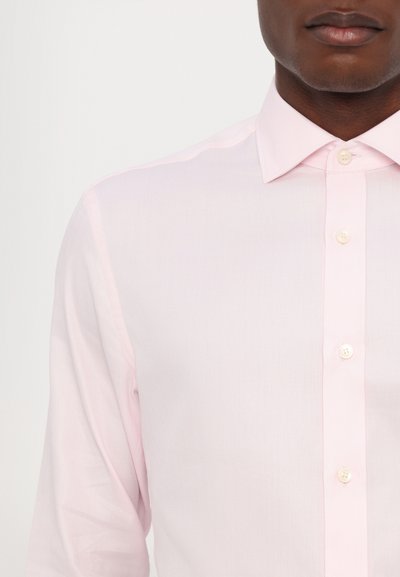 Camicia da uomo a maniche lunghe di colore rosa chiaro con trama a spina di pesce, dotata di colletto a punta e chiusura con bottoni sul davanti.