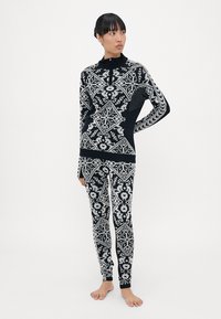 Zwart-wit patroontrui met legging set, met geometrische ontwerpen en een ritskraag op de trui. Zacht breiwerk.