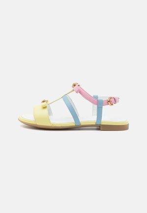Multicolored sandals featuring yellow, blue, and pink straps, gold accents, flat sole, and open-toe design. Smooth texture and adjustable buckle.