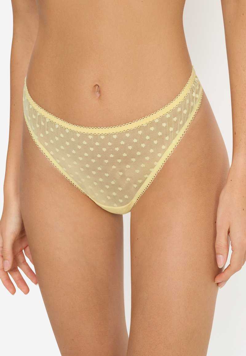 Culotte bikini en filet jaune à motif de pois, avec une délicate bordure en dentelle le long des bords et une texture douce et transparente.