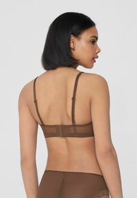 Conjunto de lencería marrón que incluye un sujetador de malla con tirantes ajustables y cierre de gancho, acompañado de braguitas a juego. Textura suave, diseño sencillo.