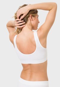 Weißes Crop-Top mit rundem Ausschnitt und breiten Schulterträgern. Weicher, elastischer Stoff mit glatter Textur, von hinten an einem Modell getragen.