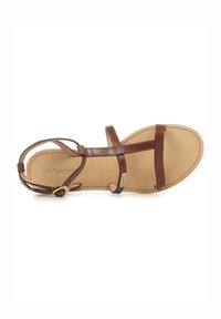 Sandalo in pelle marrone con cinturini sottili, design open toe e suola piatta beige con cuciture a contrasto e dettagli in hardware dorato.