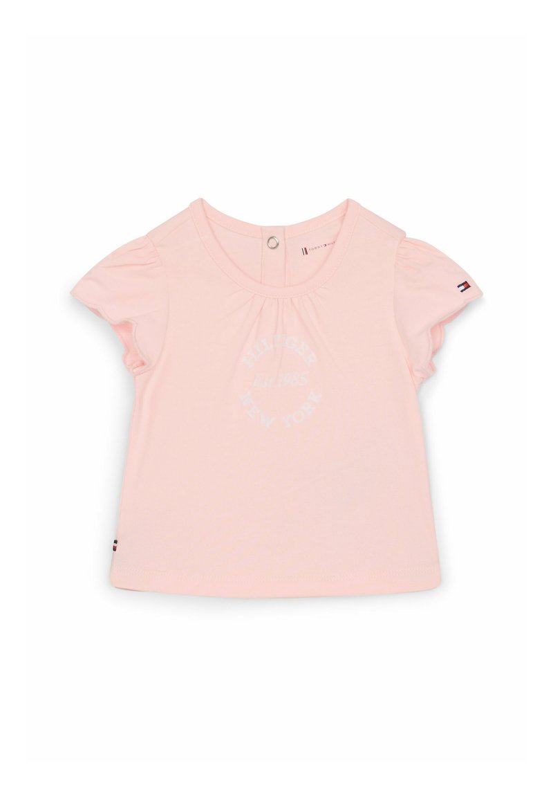 Lys rosa bomulds T-shirt med korte flæseærmer, prydet med et cirkulært logo trykt i hvidt. Knaplukning bagpå for nem påklædning.