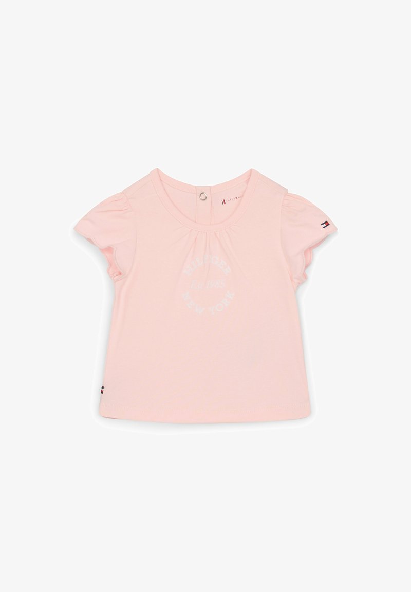 Helle rosa Baumwoll-T-Shirt mit kurzen gerafften Ärmeln, ausgestattet mit einem kreisförmigen Logo-Druck in Weiß. Druckknopfverschluss im Rücken für ein einfaches Ankleiden.