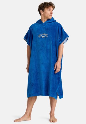 Blue terry cloth poncho with a hood, features short sleeves and a front embroidered logo. Soft texture, knee-length design.