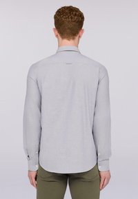 Camisa de manga larga gris claro con cuello estándar, puños abotonados y dobladillo curvado. Fabricada en una tela suave y texturizada.