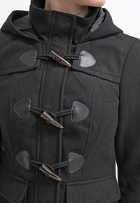 Manteau duffle en laine noire avec capuche, fermetures à boutons à bascule avec accents en cuir, et tissu texturé pour la chaleur.