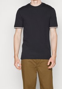 Zwart katoenen T-shirt met korte mouwen, voorzien van witte en bruine gestreepte accenten bij de manchetten en een klassieke ronde hals.