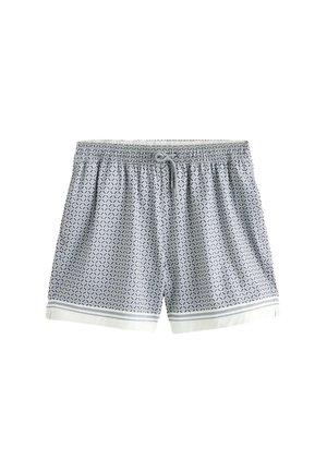 Bagudsigt af person iført blå mønstrede shorts med elastisk talje og en enkelt baglomme på beige baggrund.