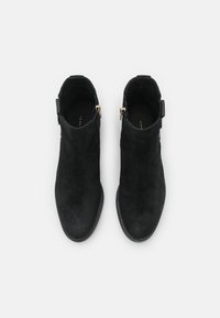 Bottines en daim noir avec un bout arrondi et une conception à hauteur de cheville. Présentent une fermeture éclair sur le côté et des accents minimalistes. Texture mate, finition lisse.