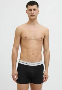 Schwarze Baumwoll-Boxershorts mit einem weißen, gebrandeten Bund. Das Design ist schlicht mit einer glatten Textur und einer figurbetonten Silhouette.