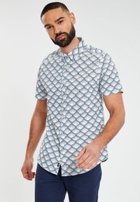 Korte mouwen overhemd met knopen met een witte basis en een geometrisch patroon in marineblauw en lichtblauw. Glad materiaal met een klassieke kraag.