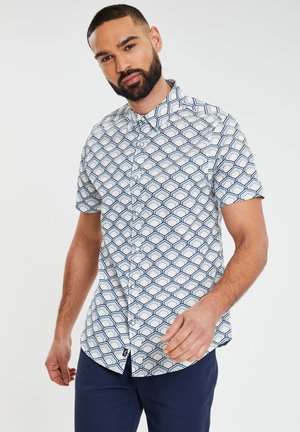 Camisa de botones de manga corta con base blanca y un patrón geométrico en azul marino y azul claro. Tejido suave con cuello clásico.