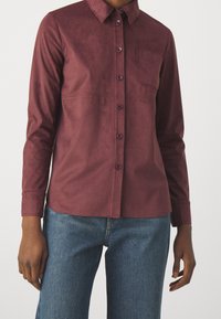 Bordowa koszula zapinana na guziki, wykonana z gładkiego materiału, z kołnierzykiem, długimi rękawami, kieszenią na piersi i subtelnymi detalami szwów.