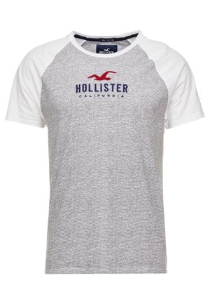 T-shirt raglan gris et blanc à manches courtes avec une mouette rouge et un texte bleu marine "Hollister California" sur la poitrine.