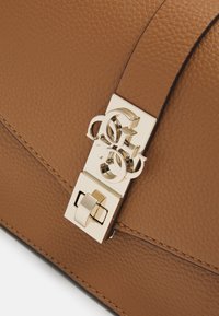 Brązowa torebka ze skóry o fakturze, wyposażona w złocisty metalowy zatrzask z splecionymi inicjałami oraz prostokątnym detalem zamka.