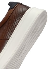 Sneaker in pelle marrone con una tomaia texture, caratterizzata da un tallone nero a contrasto e una suola in gomma bianca con un battistrada decorato.