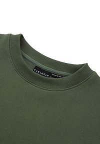 Oliwkowa bluza z prążkowanym, okrągłym dekoltem, miękką teksturą oraz metką z napisem „CARLHEIM” i rozmiarem „Kobieta M”.