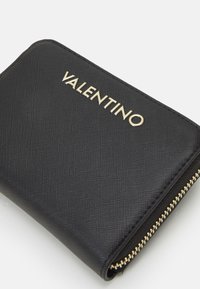Portofel negru dintr-un material texturat, cu un logo aurit "Valentino" și detalii aurii cu fermoar pe margine.