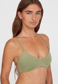 Grön triangeltopp i bikini med tunna justerbara axelband, tillverkad av textil med struktur. Har korsade detaljer på sidorna.