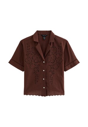 Camisa marrón de manga corta con botones, bordado floral y dobladillo con borde festoneado, que presenta un cuello con muesca y tela ligera.