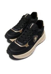 Schwarze Sportschuhe aus Mesh- und glatten synthetischen Materialien, mit goldenen Akzenten, Schnürdesign und einer dicken, cremefarbenen Zwischensohle.