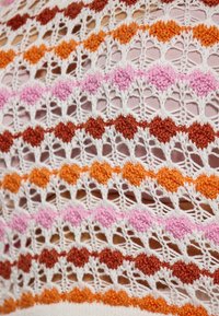 Tessuto all'uncinetto con motivi multicolori nelle tonalità di arancione, rosa e bianco; presenta un intricato design in pizzo con dettagli a lavorazione aperta.