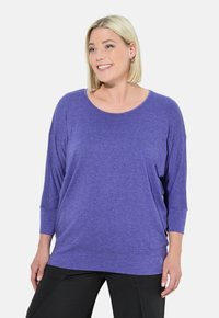 Paarse lange-sleeve top met een ronde halslijn en een losse pasvorm, gemaakt van zachte, lichte stof met een gladde textuur.