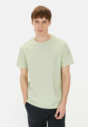 Lys grøn bomulds t-shirt med rund halsudskæring og korte ærmer, med et diskret logo i en matchende farve på venstre bryst.