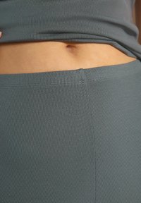Ribbad tyg topp i grått, figursydd design med en kortad längd, som har en slät söm längs fållen och en lätt textur för komfort.