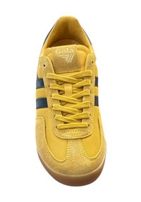 Żółte sneakersy wykonane z zamszu i siateczki, z niebieskimi paskami, okrągłymi sznurówkami oraz gumową podeszwą. Logo na języku jest wytłoczone.