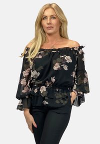 Czarna bluzka z odkrytymi ramionami z dużym kwiatowym wzorem w odcieniach różu i zieleni; ma falbaniaste rękawy i elastyczny pas.