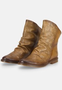 Bottines en cuir tan avec un design flou, des perforations florales et des bouts ronds. Les semelles plates et des accents latéraux discrets complètent le look.