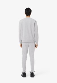 Sudadera gris y pantalones a juego, confeccionados en tejido suave, con un corte clásico, puños acanalados y un logo sutil en el cuello.