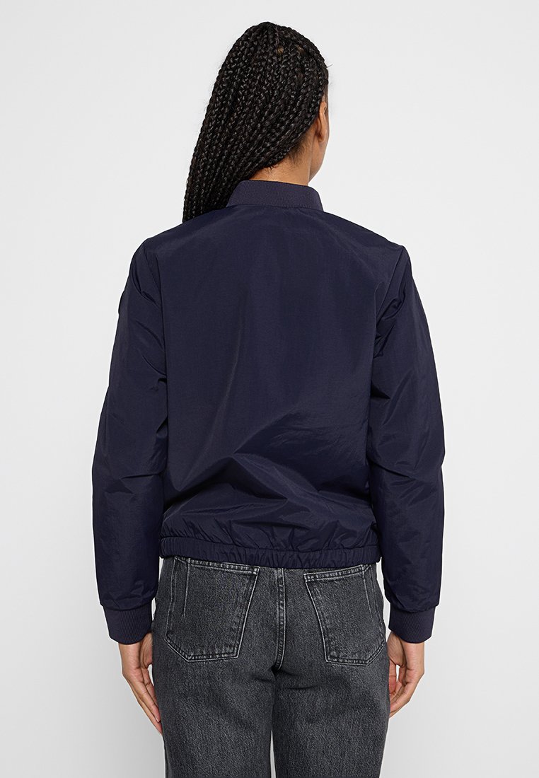 Giacca bomber blu navy con polsini e cintura elasticizzati, caratterizzata da un tessuto leggero e liscio e da un design classico del colletto.