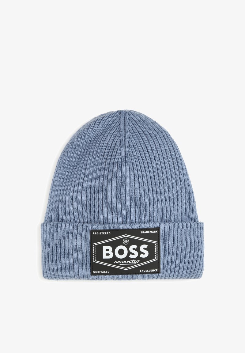 Bonnet en tricot bleu avec une texture côtelée, arborant une étiquette rectangulaire noire avec le texte blanc "BOSS seventy" et des accents de "l'excellence inégalée."