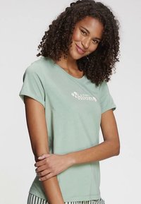 Mint green cotton t-shirt with short sleeves, featuring a white text graphic that reads “choose bloom” and subtle floral accents.